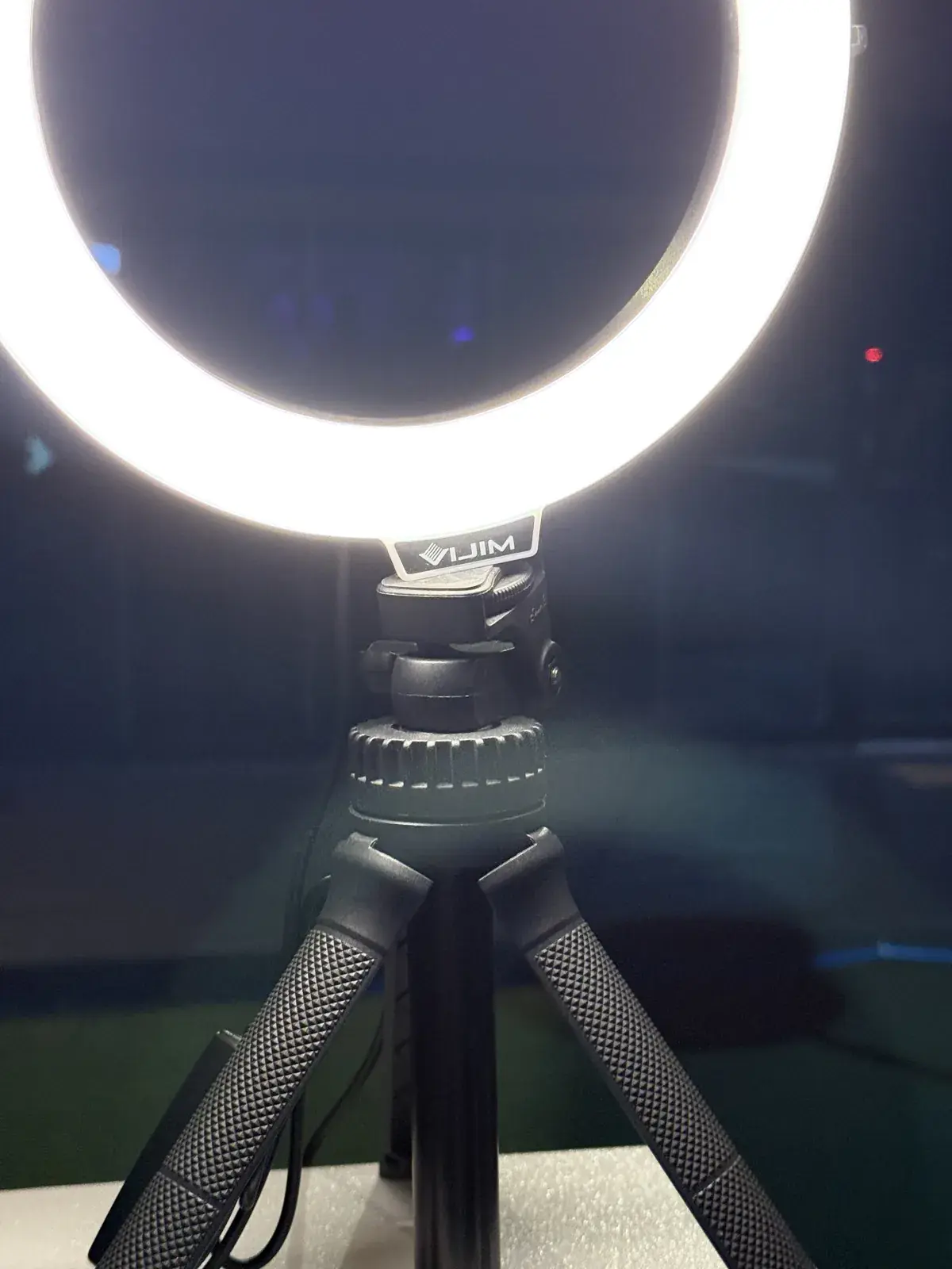 A ring light on a small tripod glowing brightly in the dark at night