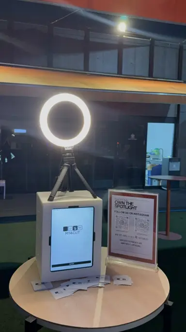 A white mini booth with an iPad on a round rooftop table in Seongsu, a ring light on a tripod above it, a sign beside it