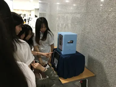 Participants gathered around a my4cut mini photo booth on a table in a demo day lobby