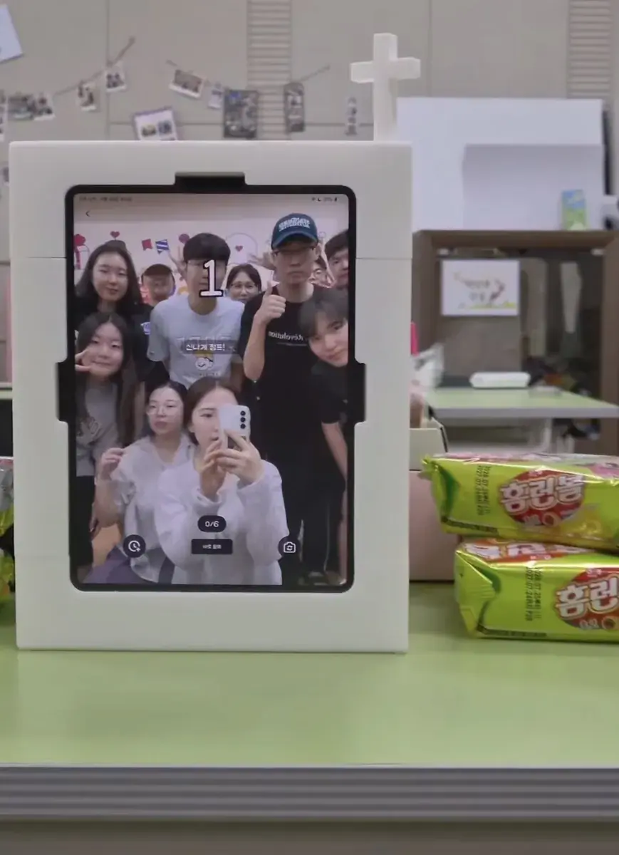 A my4cut mini photo booth showing a group four-cut on screen at a local event