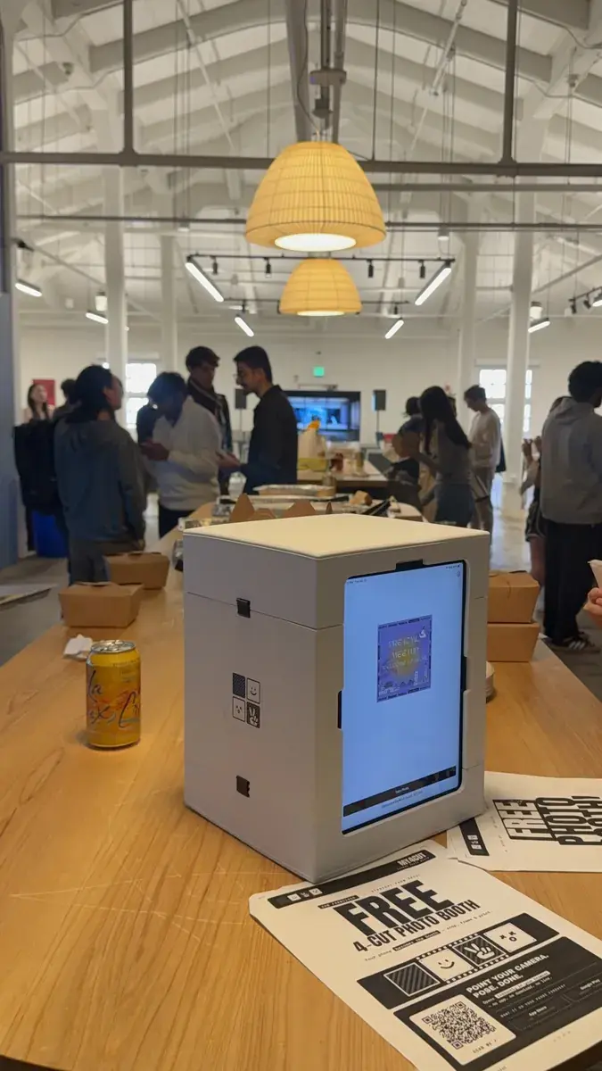 A my4cut mini booth on a café table at a San Francisco conference with attendees behind