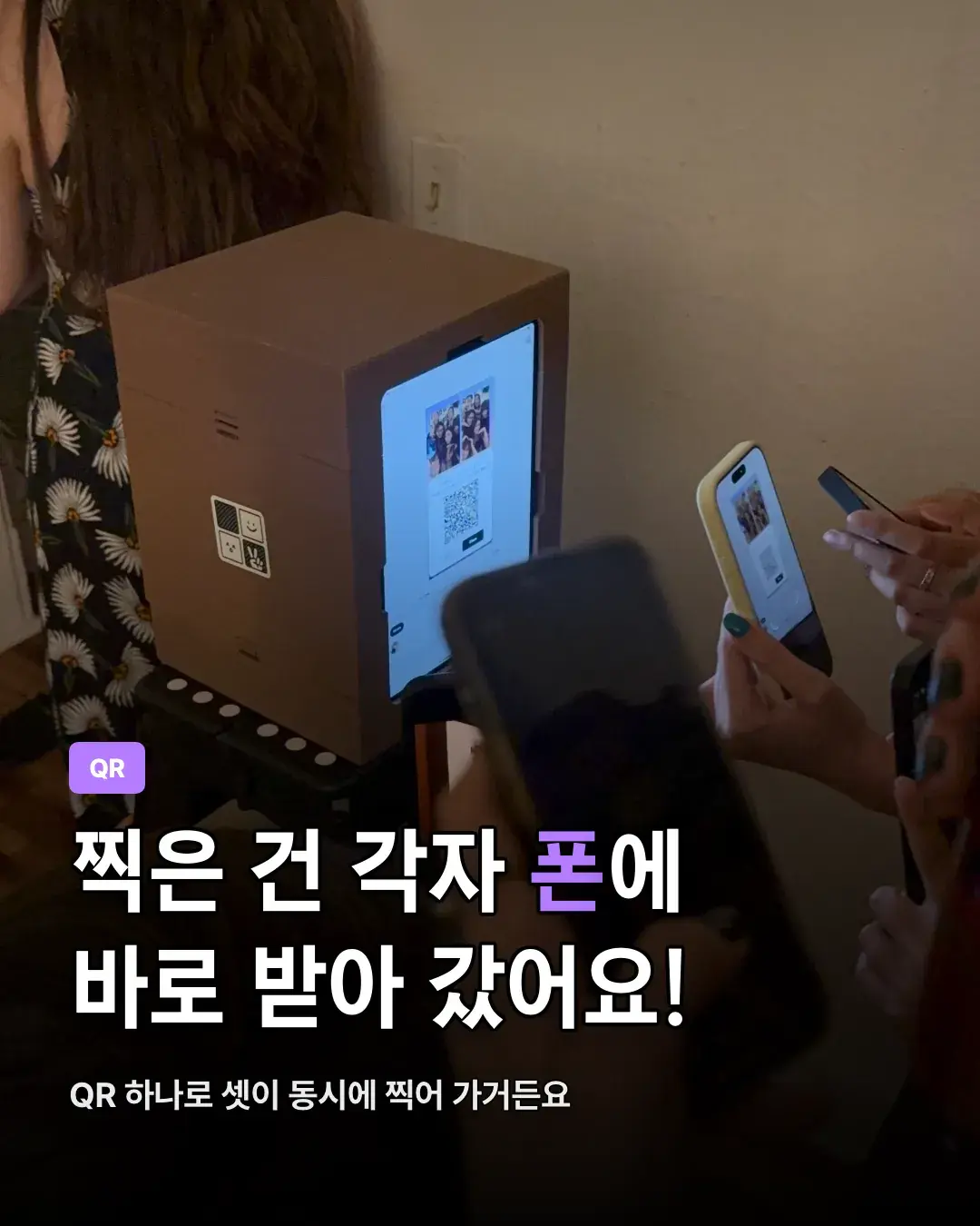 茶色のミニフォトブースの画面に出た4コマとQRコードに向けて、ゲスト3人が同時にスマホのカメラをかざしている様子