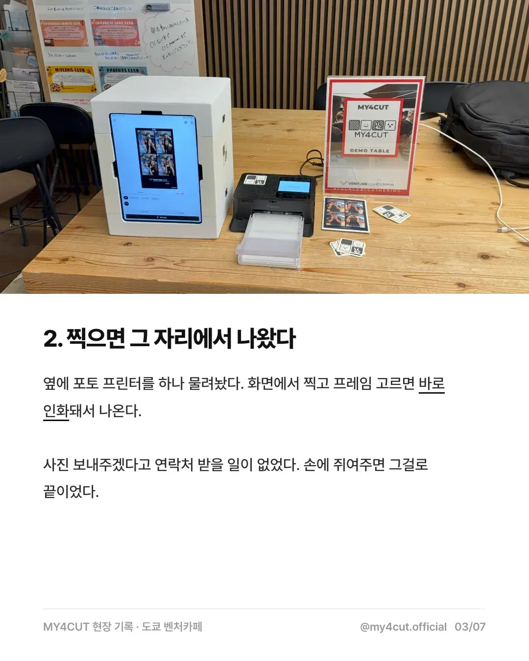 A white mini booth holding an iPad on the Venture Café Tokyo demo table, with a Canon photo printer and printed four-cut strips next to it