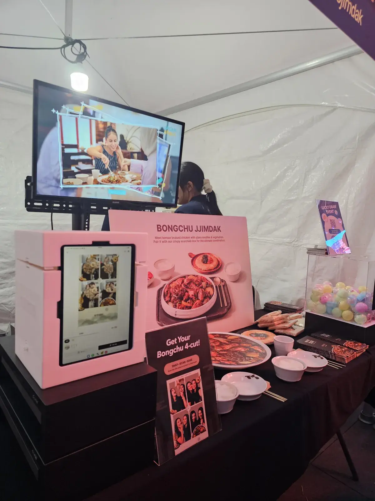 Pink MY4CUT mini booth with an iPad on a black table beside a menu board, a Get Your Bongchu 4-cut! sign and capsules