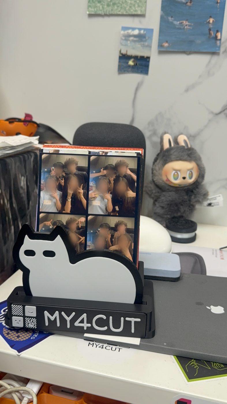 모니터 앞 책상 위에 세워 둔 거치대. 뒤 칸에 4×6 사진, 기본 MY4CUT 명판