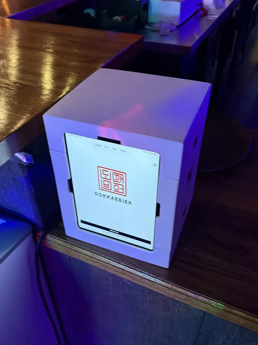 The my4cut booth on the bar counter showing a guest four-cut on screen