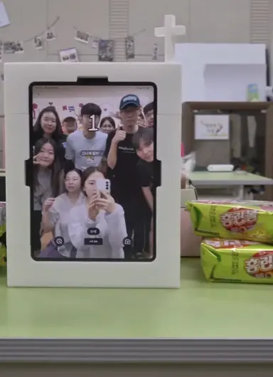 A white my4cut mini photo booth with a cross ornament showing a church youth group four-cut on screen