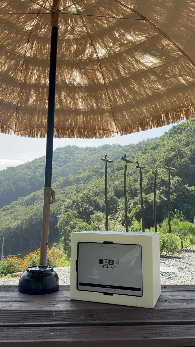A white my4cut mini booth on an outdoor table with mountains behind